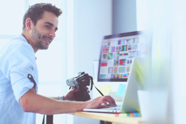 İnternette çalışırken bilgisayarın ve dizüstü bilgisayarın önünde grafik stüdyosunda oturan genç tasarımcının portresi.