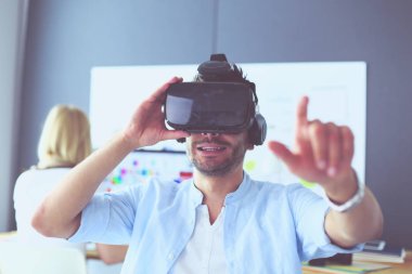 Genç erkek yazılım programcısı ofiste üç boyutlu sanal gerçeklik gözlükleriyle yeni bir uygulama test ediyor..