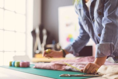 Moda tasarımcısı kadın stüdyoda tasarımları üzerinde çalışıyor.