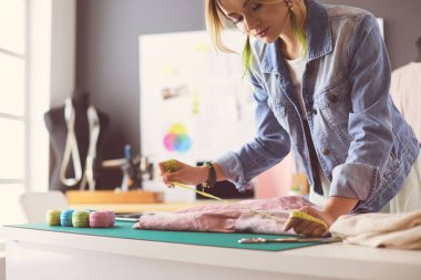Moda tasarımcısı kadın stüdyoda tasarımları üzerinde çalışıyor.