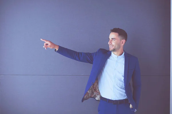 Joven empresario sentado aislado sobre fondo gris. —  Fotos de Stock