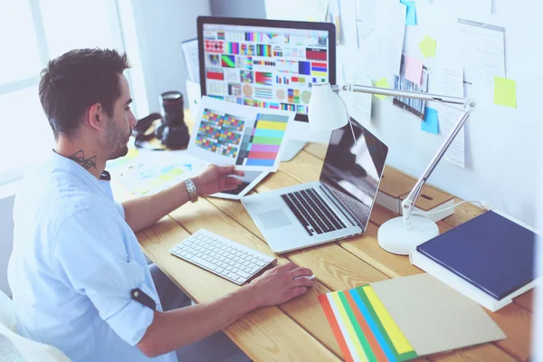 Porträt eines jungen Designers, der im Grafikstudio vor Laptop und Computer sitzt, während er online arbeitet. — Stockfoto