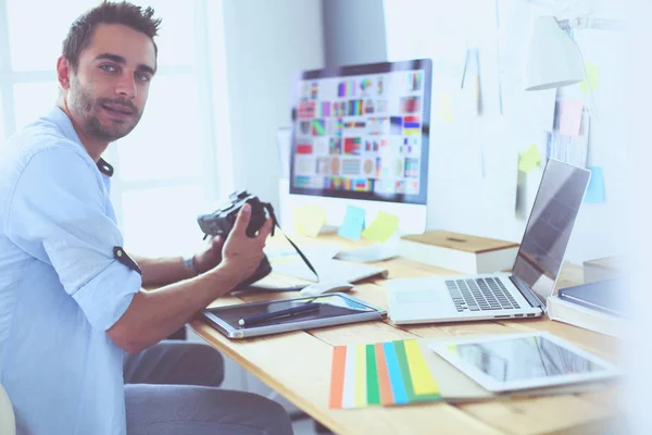 Retrato del joven diseñador sentado en el estudio gráfico frente a la computadora portátil y el ordenador mientras trabaja en línea. — Foto de Stock