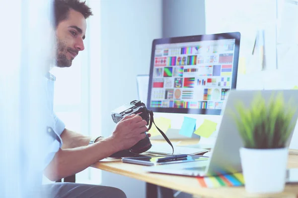 Porträt eines jungen Designers, der im Grafikstudio vor Laptop und Computer sitzt, während er online arbeitet. — Stockfoto