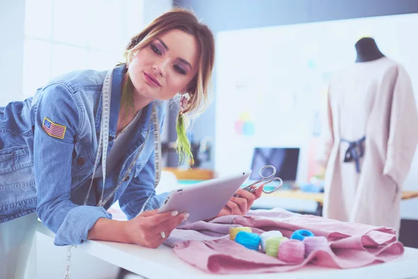 Diseñadora de moda mujer que trabaja con ipad en sus diseños en el estudio —  Fotos de Stock