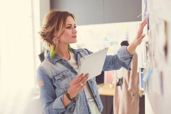 Diseñadora de moda mujer trabajando en sus diseños con ipad en el estudio —  Fotos de Stock