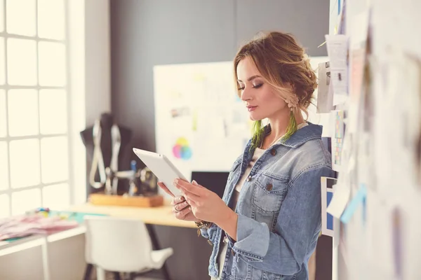 Donna stilista che lavora sui suoi disegni con ipad in studio — Foto Stock