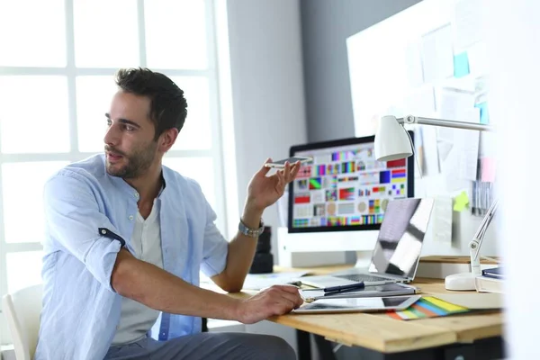 Porträt eines jungen Designers, der im Grafikstudio vor Laptop und Computer sitzt, während er online arbeitet. — Stockfoto