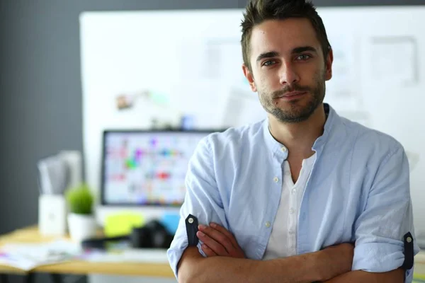 Retrato del joven diseñador delante de la computadora portátil y el ordenador mientras trabaja. Asistente usando su móvil en segundo plano . —  Fotos de Stock