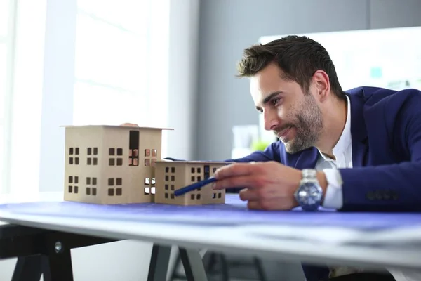 Homme d'affaires tenant maison miniature à portée de main debout dans le bureau . — Photo