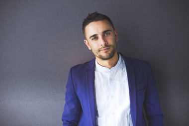 Gri arka planda yalnız oturan genç iş adamı.