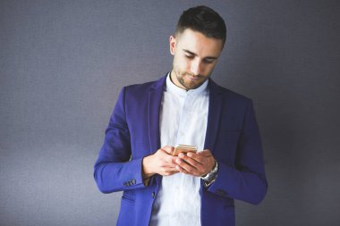 Gri arka planda yalnız oturan genç iş adamı.