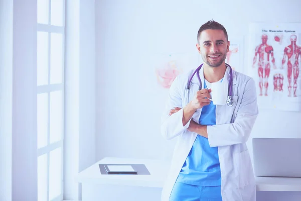 Jonge en zelfverzekerde mannelijke arts portret staan in medische off — Stockfoto