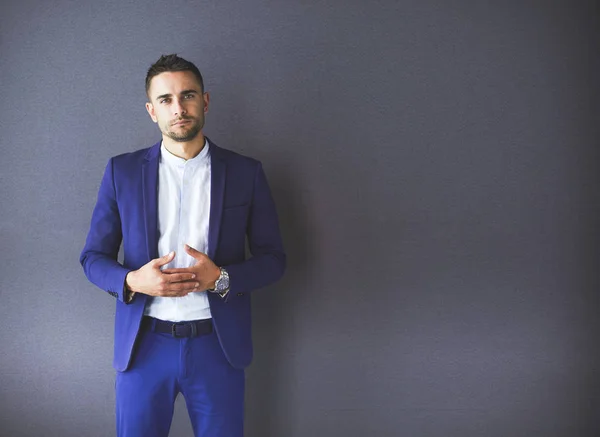 Joven empresario sentado aislado sobre fondo gris. —  Fotos de Stock