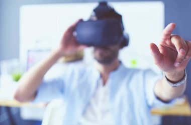 Genç erkek yazılım programcısı ofiste üç boyutlu sanal gerçeklik gözlükleriyle yeni bir uygulama test ediyor..