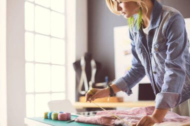Moda tasarımcısı kadın stüdyoda tasarımları üzerinde çalışıyor.