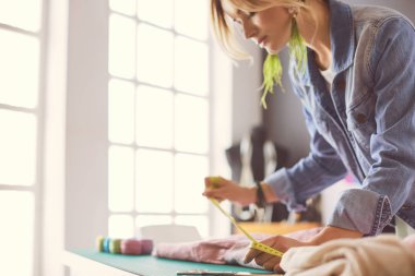 Moda tasarımcısı kadın stüdyoda tasarımları üzerinde çalışıyor.