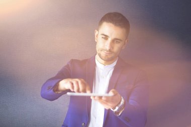 Gri arka planda yalnız oturan genç iş adamı.