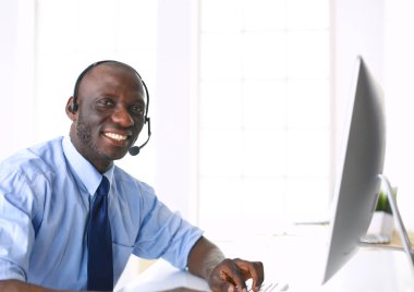 Kulaklıklı Afro-Amerikan işadamı laptopuyla çalışıyor.