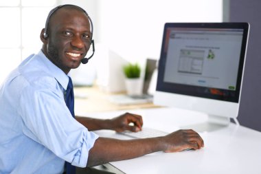 Kulaklıklı Afro-Amerikan işadamı laptopuyla çalışıyor.