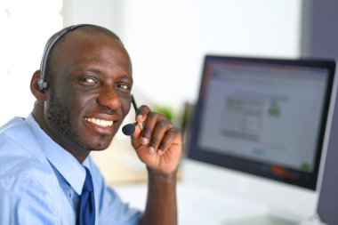 Kulaklıklı Afro-Amerikan işadamı laptopuyla çalışıyor.