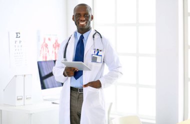 Tablet bilgisayarlı siyahi bir doktor hastanede bekliyor.