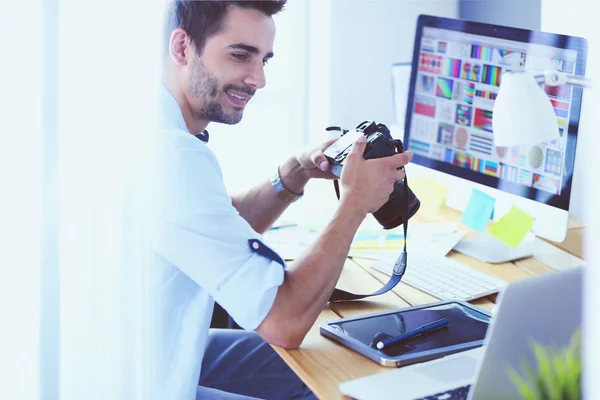 Retrato del joven diseñador sentado en el estudio gráfico frente a la computadora portátil y el ordenador mientras trabaja en línea. — Foto de Stock