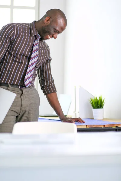 Arquiteto afro-americano trabalhando com computador e plantas no escritório — Fotografia de Stock