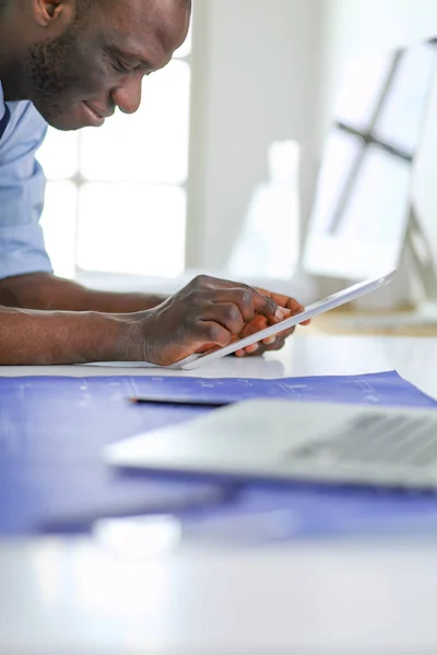 Arquitecto afroamericano trabajando con computadoras y planos en la oficina —  Fotos de Stock