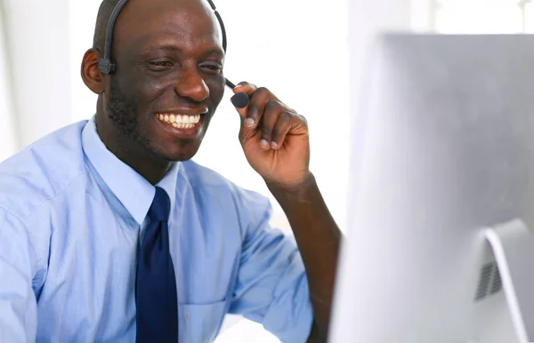 Afrikansk amerikansk affärsman på headset arbetar på sin bärbara dator — Stockfoto