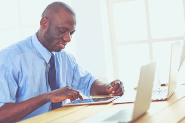 Kulaklıklı Afro-Amerikan işadamı laptopuyla çalışıyor.