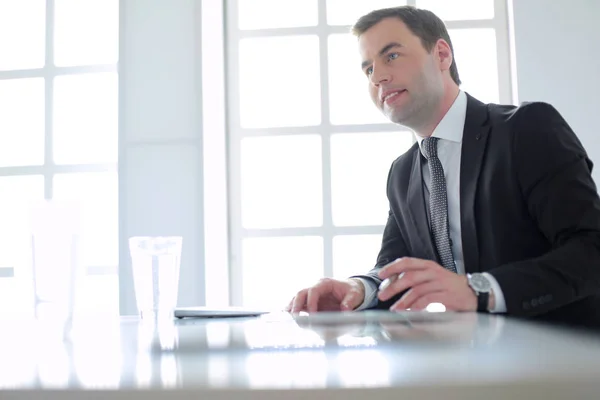 Porträt eines jungen Mannes, der an seinem Schreibtisch im Büro sitzt. — Stockfoto