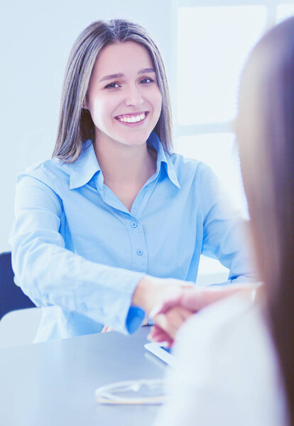 Two female colleagues in office sitting on the desk