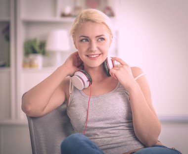 Evdeki genç ve güzel kadın kanepede oturup müzik dinliyor.