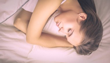 Genç ve güzel bir kadın yatakta yatıyor.