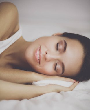 Genç ve güzel bir kadın yatakta yatıyor.