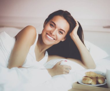 Genç ve güzel bir kadın yatakta yatıyor.