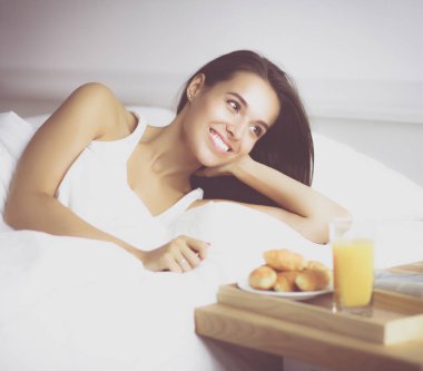 Genç ve güzel bir kadın yatakta yatıyor.