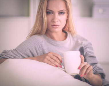 evde kanepenin üzerine bir fincan genç güzel kadın