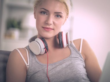 Evdeki genç ve güzel kadın kanepede oturup müzik dinliyor.