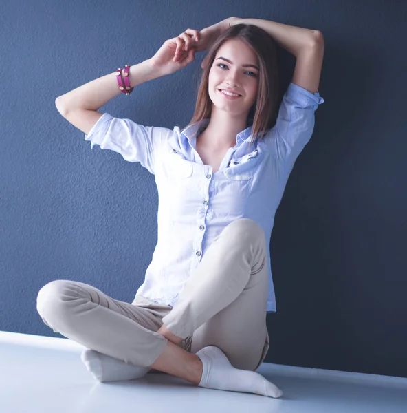 Jonge vrouw zit op de vloer in de buurt van donkere muur — Stockfoto