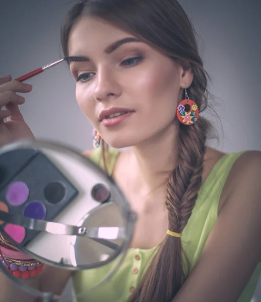 Joven hermosa mujer haciendo maquillaje cerca del espejo — Foto de Stock