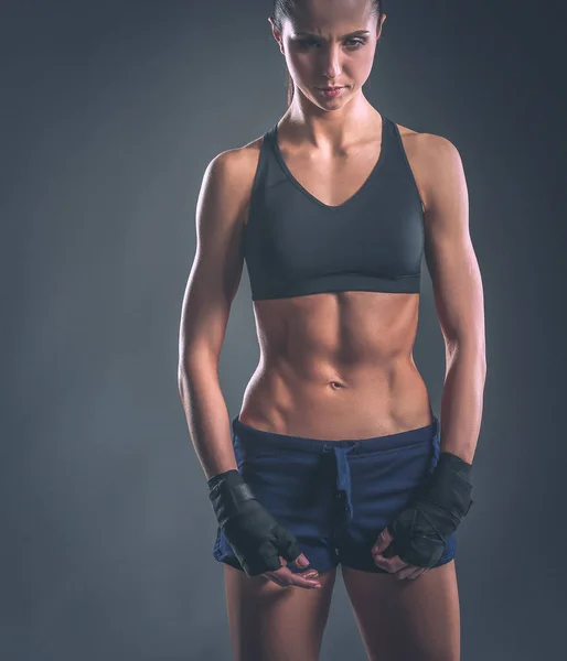 Gespierde jonge vrouw poseren in sportkleding tegen zwarte achtergrond — Stockfoto