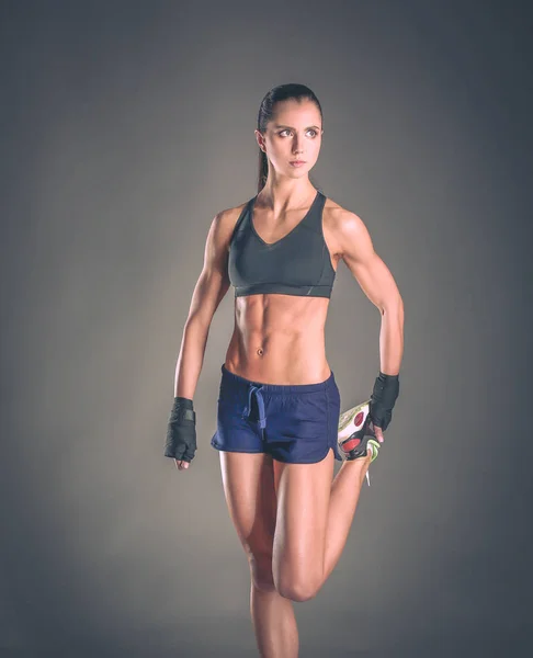 Gespierde jonge vrouw poseren in sportkleding tegen zwarte achtergrond — Stockfoto