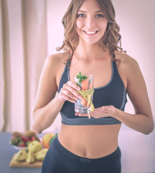 Mujer sosteniendo un vaso lleno de ensalada de frutas frescas con una cinta métrica alrededor del vaso — Foto de Stock