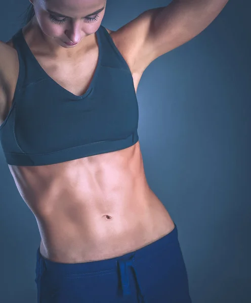 Muscular young woman posing in sportswear against black background — Stock Photo, Image