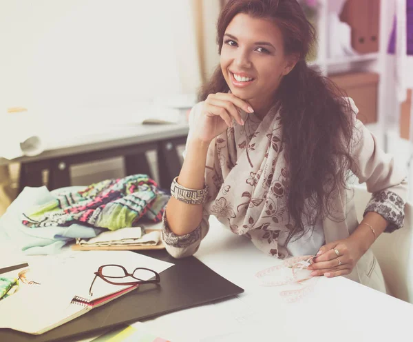 Leende kvinnlig modedesigner sitter vid skrivbordet — Stockfoto