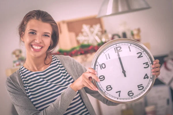 Happy young woman showing clock in christmas decorated kitchen — Stock Photo, Image