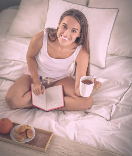 Joven hermosa mujer sentada en la cama — Foto de Stock