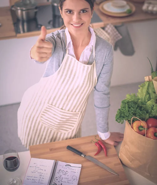 Vrouw met boodschappentassen in de keuken thuis, bij het bureau — Stockfoto